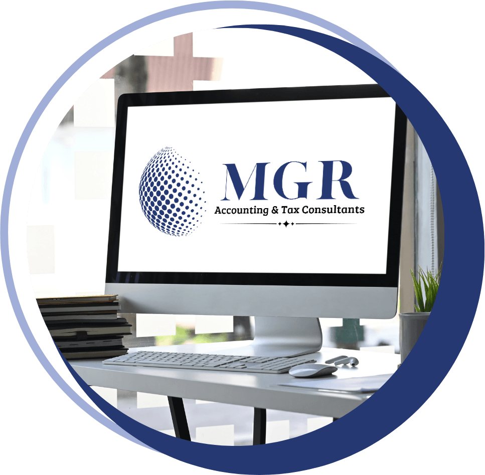 desktop-monitor-mgr-logo-circle large monitor with the MGR Accounting & Tax Consultants logo on the screen, sitting on a desk next to a keyboard, mouse, and a stack of books in an accounting office